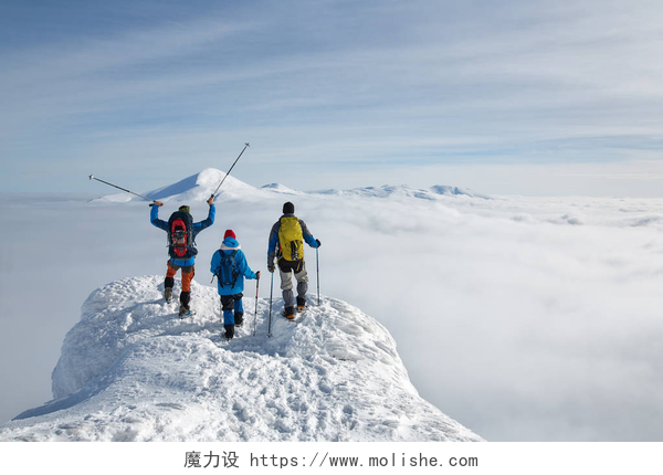 登上雪山山顶的三个人远足者在云层之上